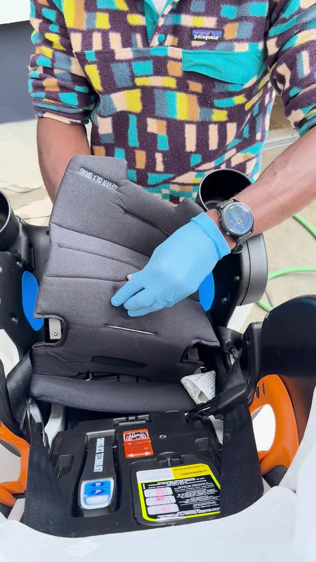 Mark in a patterned fleece and blue gloves, fitting a freshly washed pad back onto a car seat